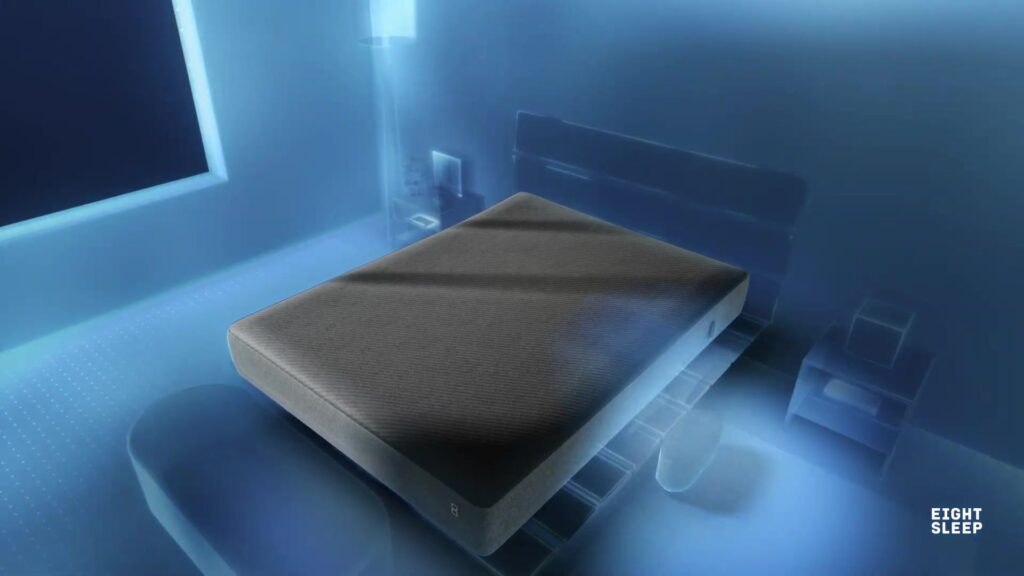 Matras met het grijze Pod 6-dek van Eight Sleep in een slaapkamer in blauw licht