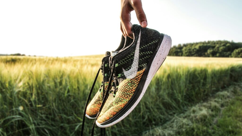 Hardloopschoenen en een sporttas naast een opgemaakt bed in de avond