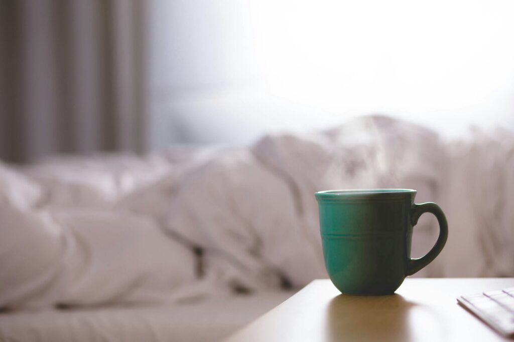 Teruggeslagen dekbed op een bed bij een open raam in de ochtend