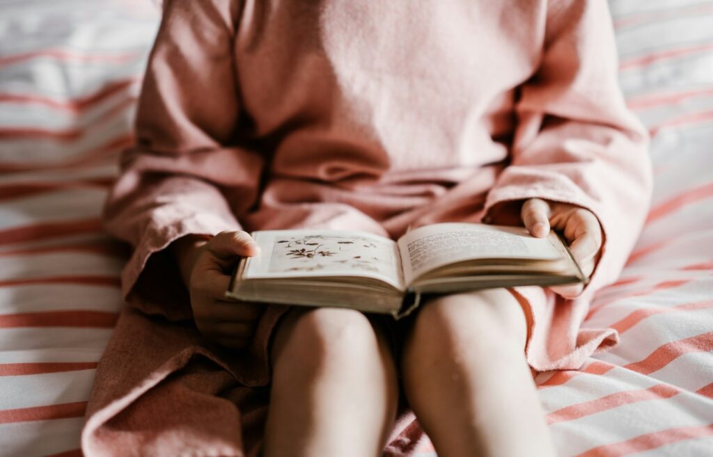 Ouder leest een kind voor in bed bij gedimd licht