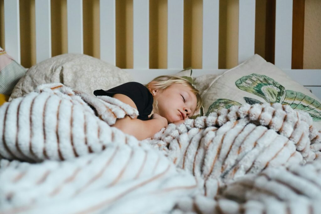 Kind slaapt in een bed met een lichtgekleurd dekbed