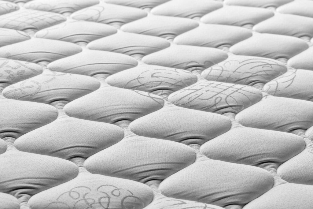Matrastopper op een opgemaakt bed in een lichte slaapkamer