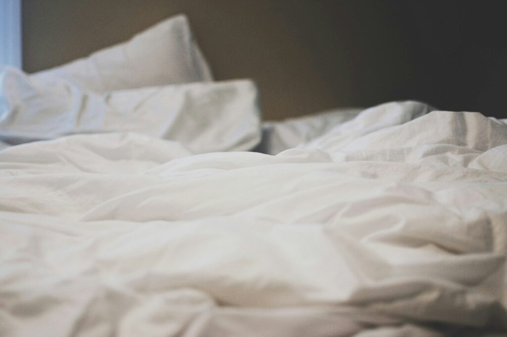 Opengeslagen dekbed op een bed met linnen beddengoed in ochtendlicht