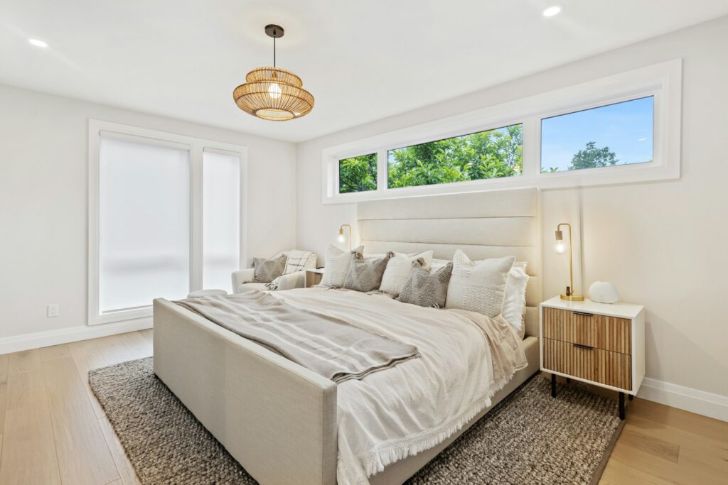 Opgemaakt bed in een lichte slaapkamer met een raam op een kier