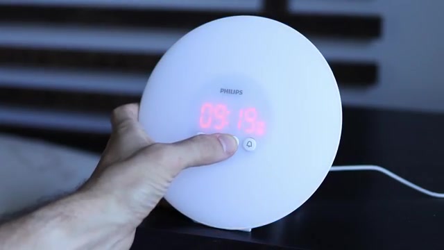 Hand die de wektijd instelt op een wekkerlicht naast het bed