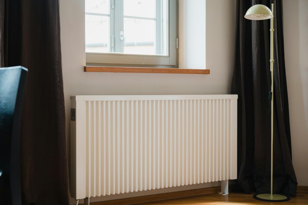 Witte radiator onder het raam van een slaapkamer