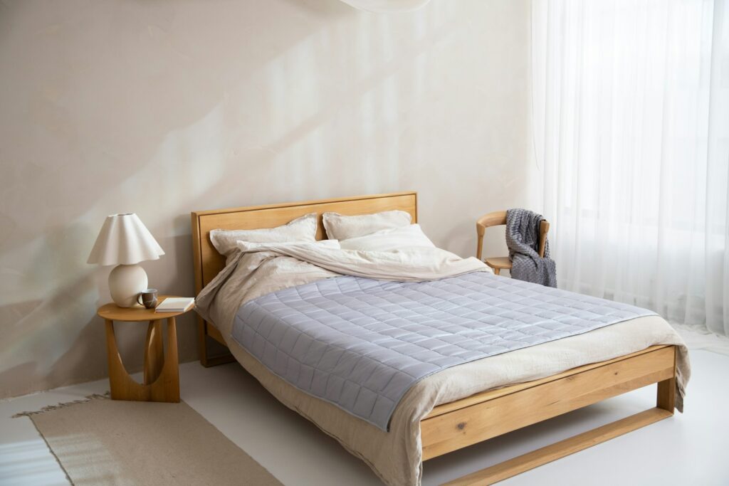 Opgemaakt bed met een dekbed en een plaid aan het voeteneind in herfstlicht
